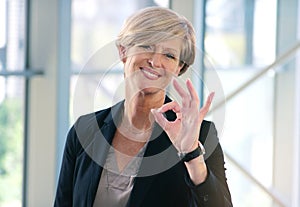 Portrait, smile and business woman with ok sign in office for success, agreement or yes. Face, mature and female