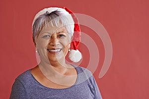 Portrait, smile and Christmas hat with senior woman, retirement and happiness on red studio background. Face, old person