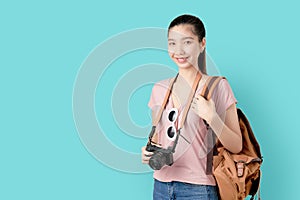 Portrait smile happily Asian woman ready to travel, tourism and vacation with backpack, photo camera on blue background.