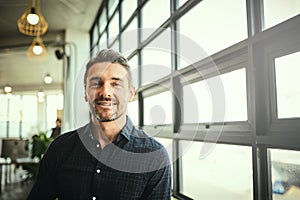 Portrait, smile and happy man at office window, creative startup and business project for entrepreneur at design agency