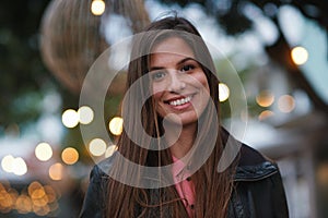 Portrait, smile and happy with a woman outdoor in the city during the evening on a blurred background. Face, holiday and