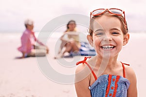 Portrait, smile and little girl on beach in summer with family for travel, holiday or vacation. Face, relax and sunshine