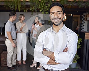 Portrait, smile and a professional business man in the office, standing arms crossed with his team in the background