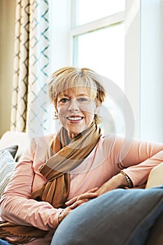 Portrait, smile or senior woman in living room to relax with joy on couch or sofa at home. Apartment, calm or happy