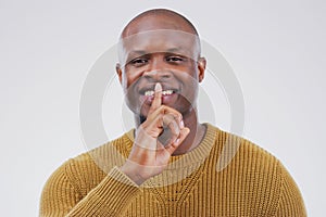 Portrait, smile and shush with private black man in studio isolated on gray background for mystery. Face, finger on lips