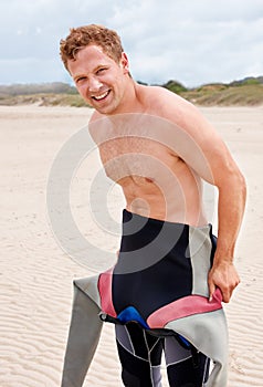 Portrait, smile and surfer man in wetsuit at beach for sports, fitness or exercise on summer vacation. Travel, health