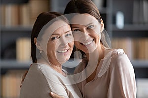 Portrait of smiling adult mom and daughter posing together