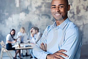 Portrait of smiling African American business man with executives working in background.