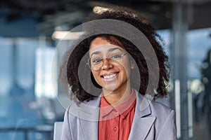 Portrait of a smiling African American businesswoman sitting in the office facing the camera and smiling. Close-up photo