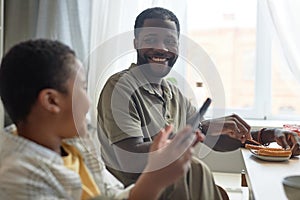Smiling Father Looking at Son at Kitchen Table