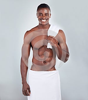 Portrait of a smiling African American fitness model posing topless in a towel and looking muscular. Happy black male