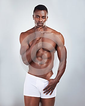 Portrait of a smiling African American fitness model posing topless in a underwear and looking muscular. Happy black