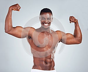 Portrait of a smiling African American fitness model posing topless in a underwear and looking muscular. Happy black