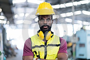 Portrait of smiling African American industrial worker man with helmet crossed arms in industry factory .happy confidence black