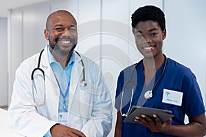 Portrait of smiling african american male and female doctor in hospital corridor