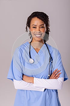 Portrait of smiling african american mid adult female doctor with arms crossed over white background