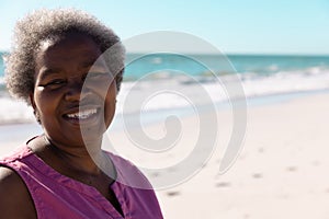 Portrait of smiling african american senior woman with gray short hair against sea and clear sky