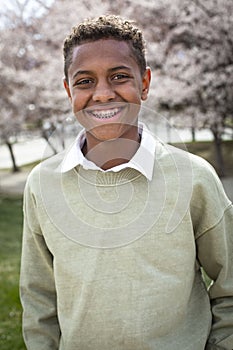 Portrait of smiling African American teenage boy with braces wearing a sweater outdoors