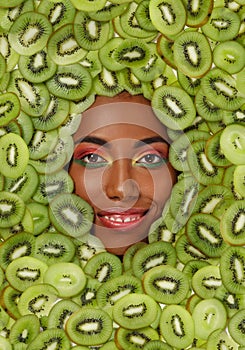 Portrait of smiling African American woman against the background of sliced kiwi fruit