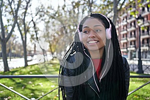 Portrait of a smiling African-American woman with a cell phone is chatting or listening to music on the streets of the city. The