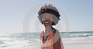Portrait of smiling african american woman looking at camera on sunny beach
