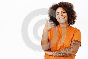 Portrait of smiling african american woman shows thumbs up, nod in approval, recommends, likes smth good, standing over