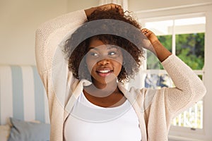 Portrait of smiling african american woman touching her hair sitting on sofa at home