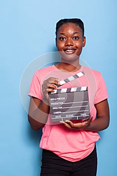 Portrait of smiling african american young woman holding filmography clapboard