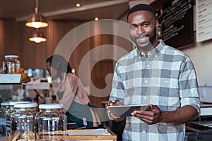 Smiling African entrepreneur working at the counter of his cafe photo