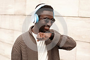 Portrait smiling african man with smartwatch using voice command recorder or takes calling in wireless headphones