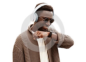 Portrait of smiling african man with smartwatch using voice command recorder or takes calling in wireless headphones listening to