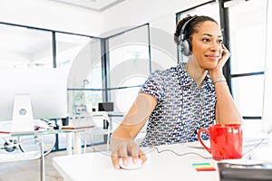 Portrait of smiling afro-american office worker sitting in offfice with headphones