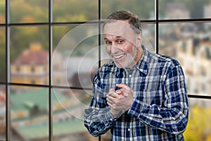 Portrait of a smiling aged businessman in office rubbing his hands.