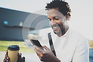 Portrait of Smiling American African man in headphone at sunny city with coffee in take away cup and enjoying to listen