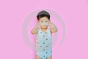 Portrait of smiling asian baby boy pointing at camera isolated over pink background