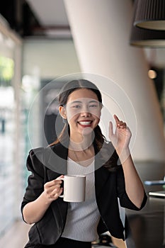 portrait smiling asian business woman pointing up and looking at the camera in modern office