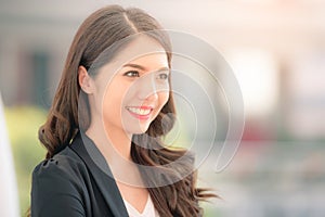 Portrait of a smiling asian businesswoman standing with arms folded on blurred city background. Business concept