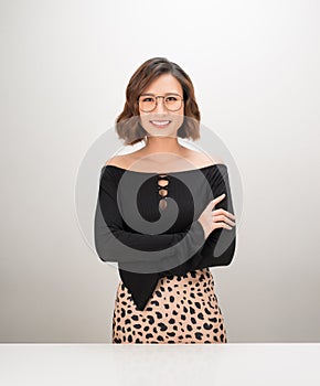 Portrait of a smiling asian businesswoman standing with arms folded and looking at camera isolated over white background