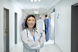 Portrait of smiling asian female doctor in busy hospital corridor, copy space