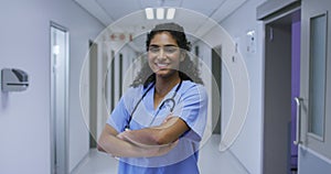 Portrait of smiling asian female doctor wearing scrubs standing in hospital corridor
