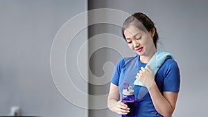 Portrait smiling Asian female fitness instructor holding bottle of water and towel looking at camera