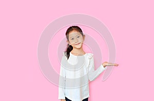 Portrait of smiling asian little child girl with showing expression hand holding something without theme isolated on pink