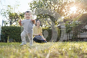 Portrait of Smiling Asian Little child son and his young mother in nature with sunlight, Happy family home