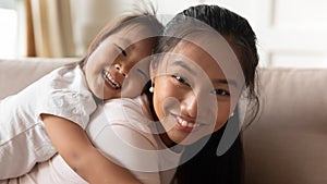 Portrait of smiling Asian mom and little daughter at home