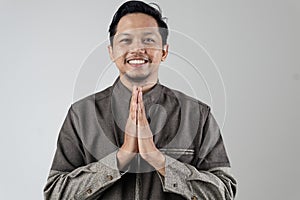 Portrait of a smiling Asian Muslim man giving a peaceful greeting to the person in front of him