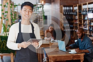 Portrait of smiling asian small business owner in his restaurant holding a wireless digital tablet. Young businessman