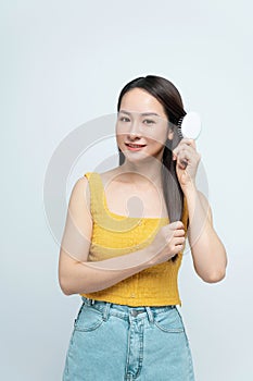 Portrait of smiling asian woman brushing her hair