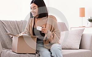 Happy asian woman unpacking parcel with beauty box