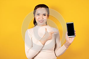 Portrait of smiling Asian woman wears cream sweater pointing on blank screen of smart phone