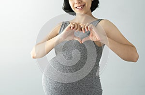 Portrait of smiling Asian young Pregnant woman showing heart shape gesture with two hands